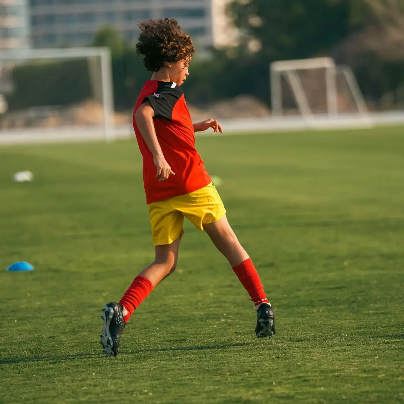 A boy in football gear kicking a ball on the field during a training session before IBER Cup.