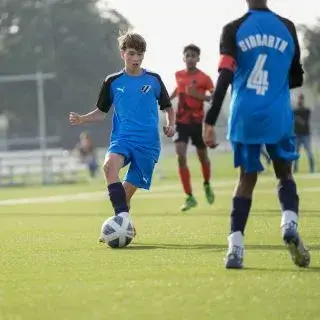 A group of young boys playing football on a grassy field.