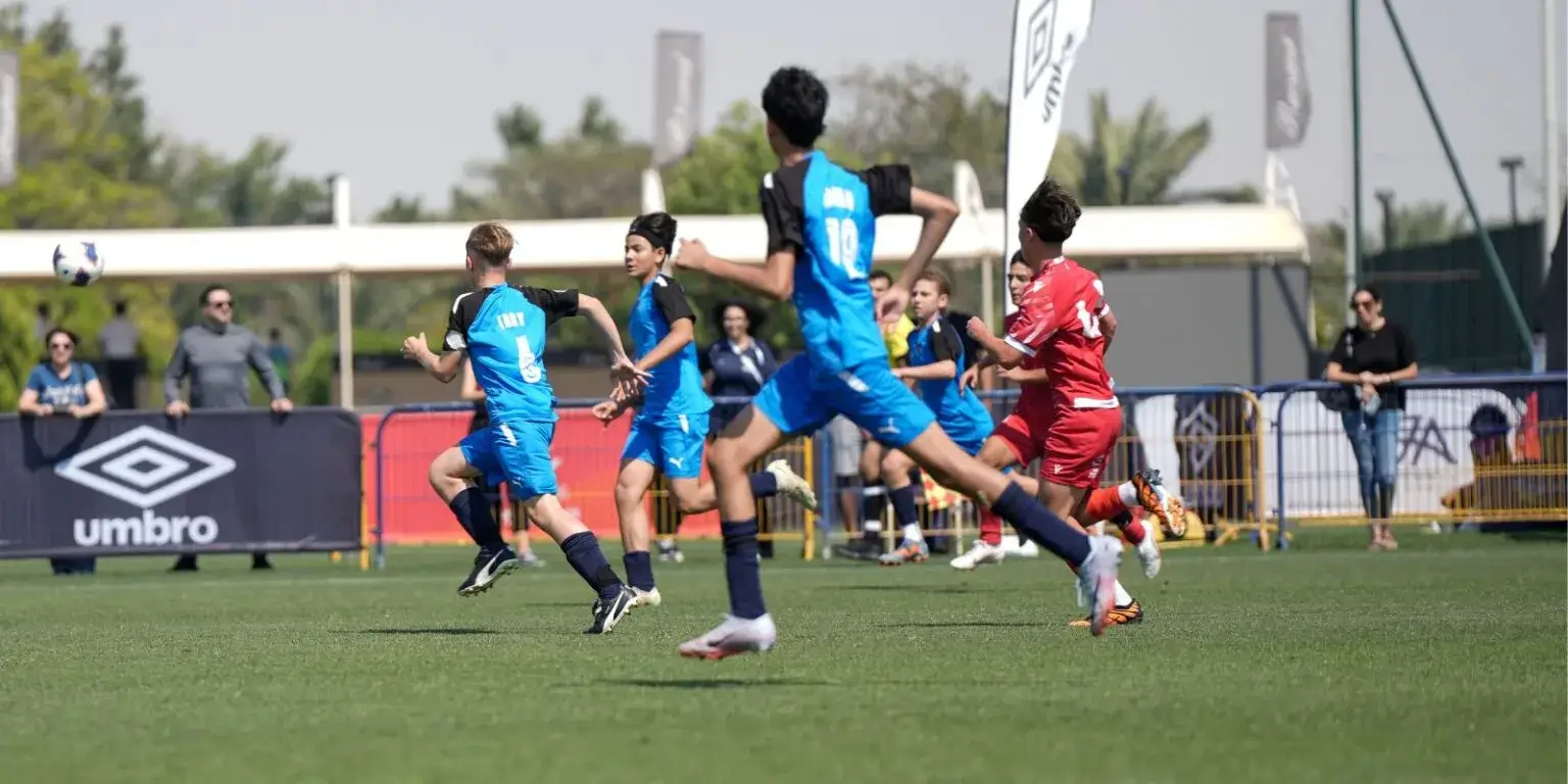 A group of young men playing soccer on a field during a sunny day.