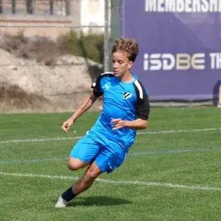 A player in blue chasing a soccer ball on the field.