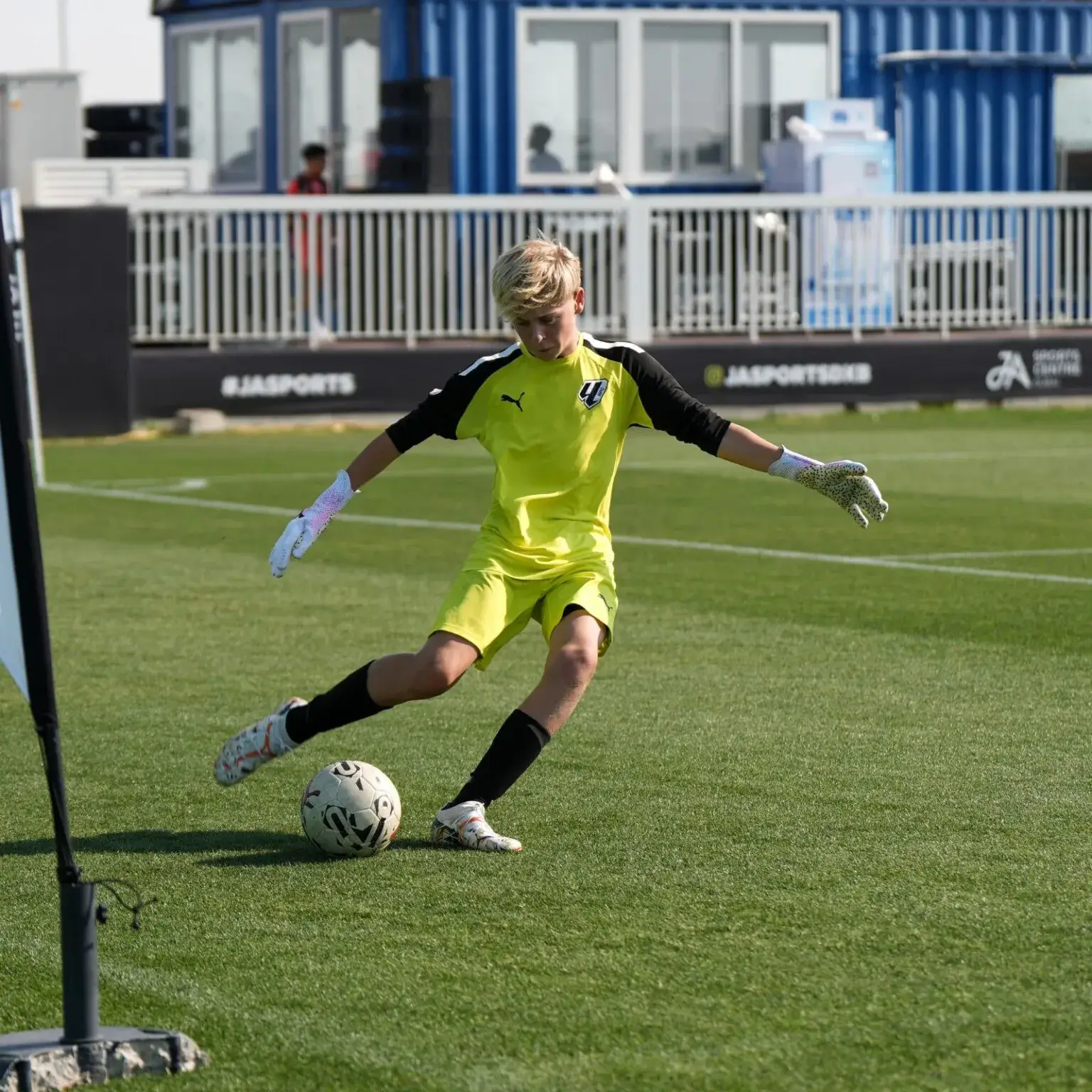 A soccer player lying on the ground next to a goal, looking exhausted after Mina Cup 2024.