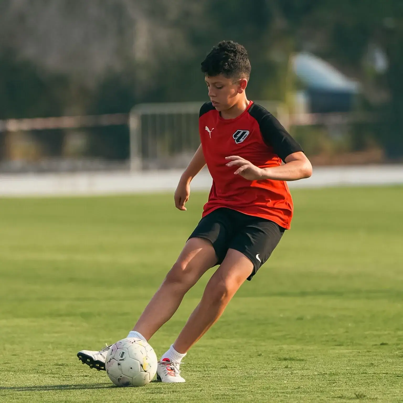 A young boy happily playing football | IBER Cup.