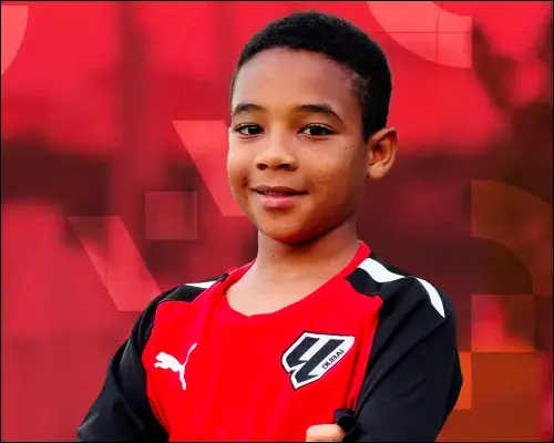 A young boy in a red and black soccer uniform at Open Trials in LaLiga Academy Dubai.