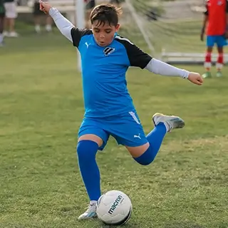 Boy Kicking Soccer Ball During Kids Football Game