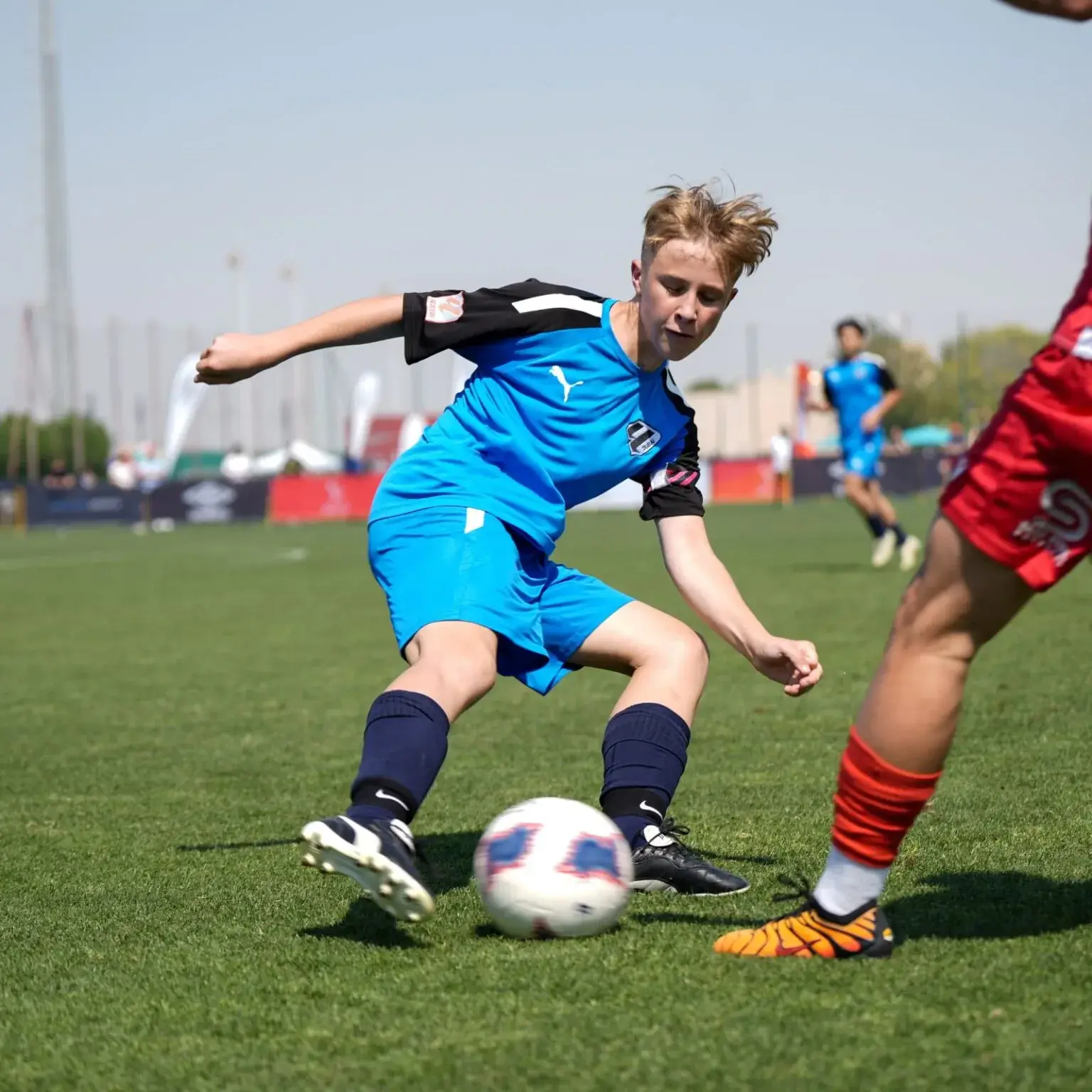 Mina Cup 2024 | A young boy wearing a blue shirt kicks the ball on the field