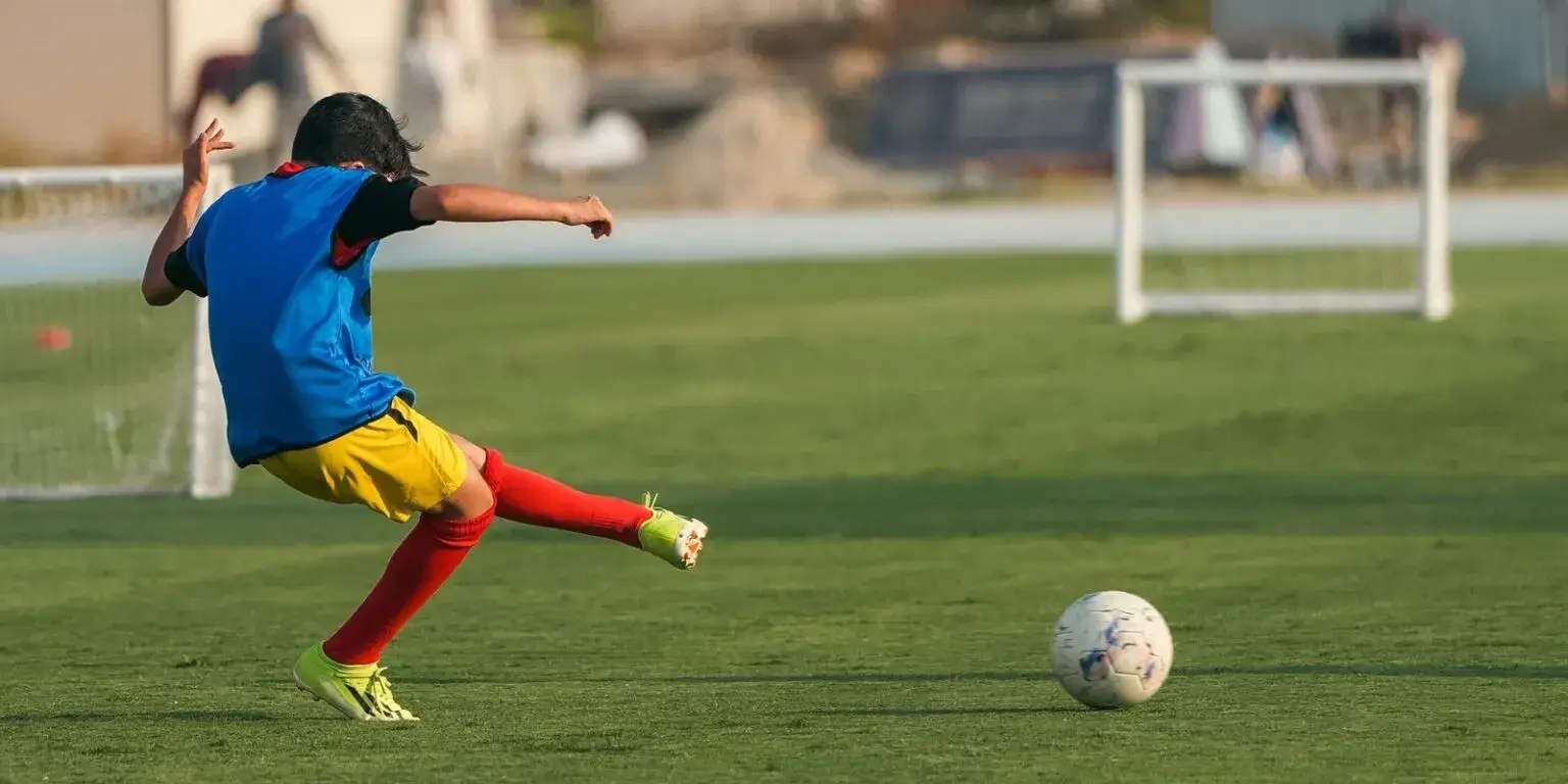 A young boy kicks a soccer ball on a field during the last training session before IBER Cup.