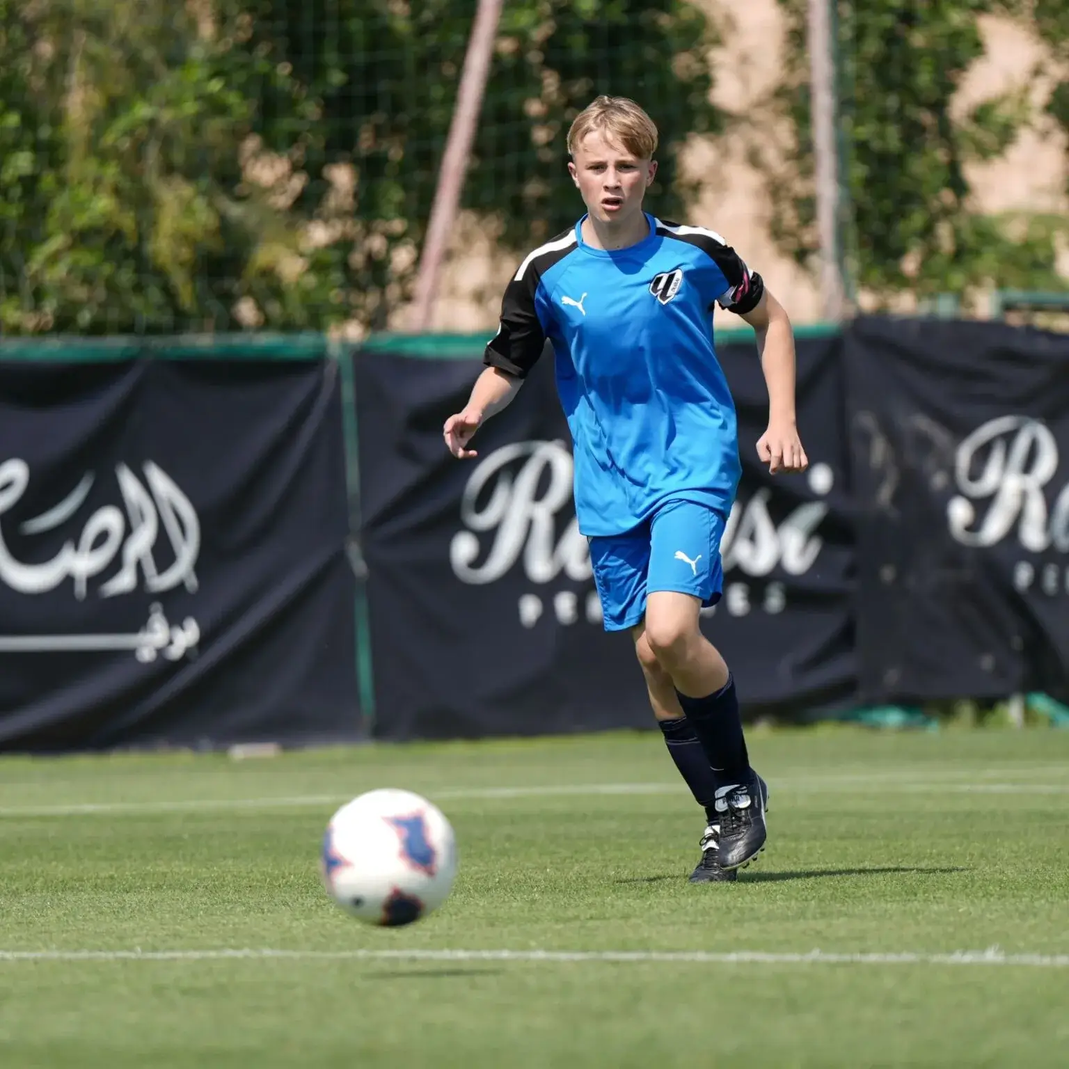 Mina Cup 2024 | A young player in blue playing soccer on a field