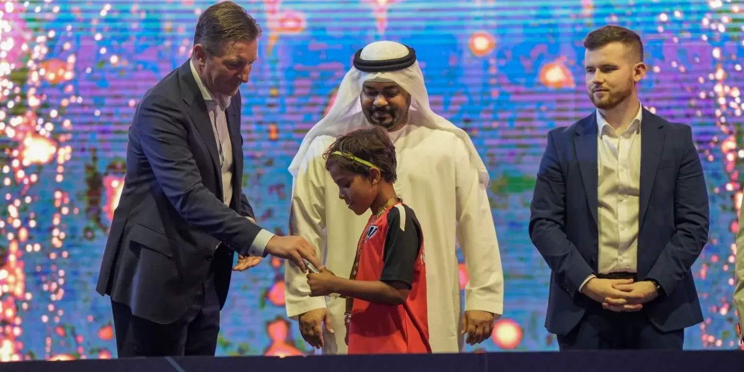 DOFA Season 2023 | Two men and a boy standing on stage as the boy receives a prize