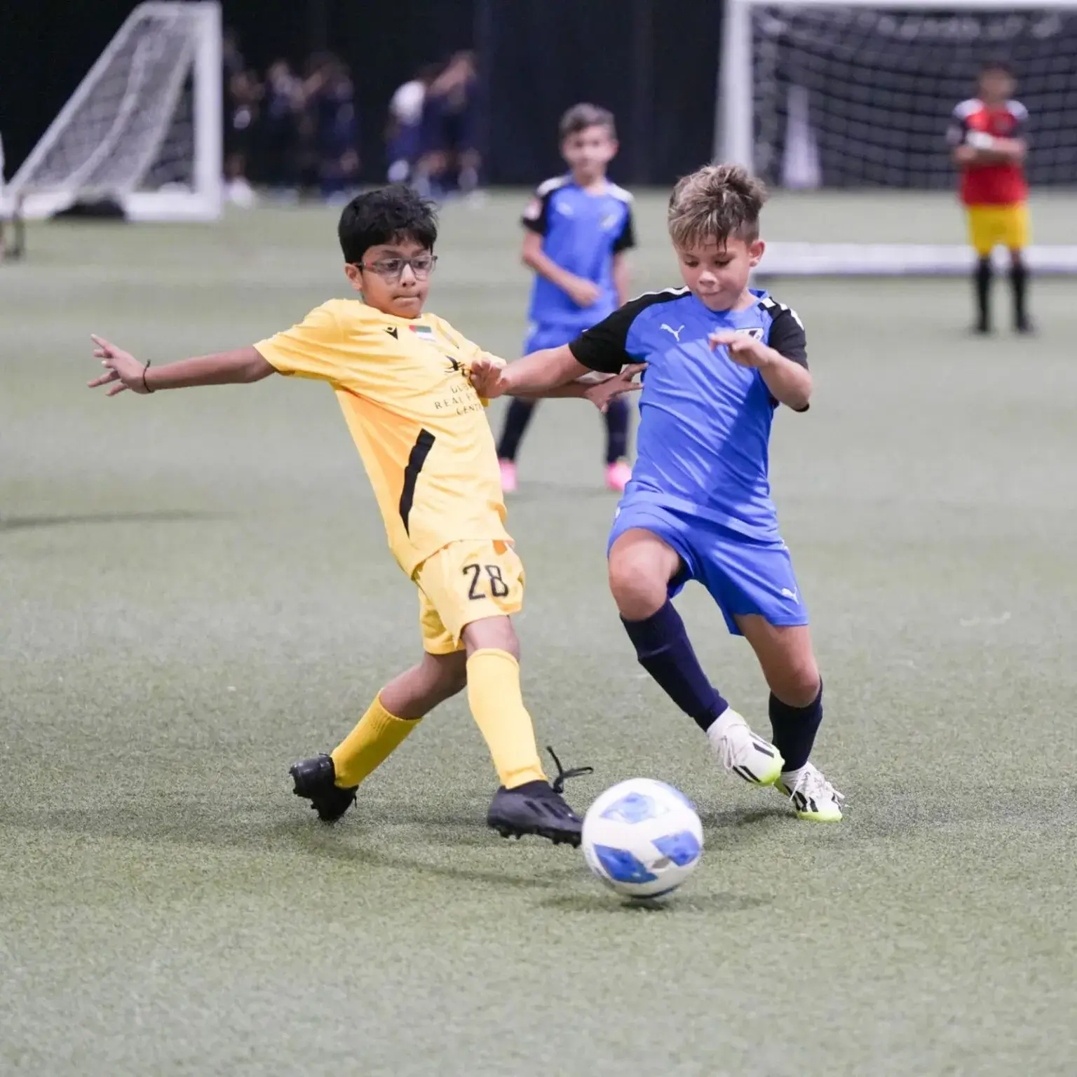 Two young boys playing football on a grass field.