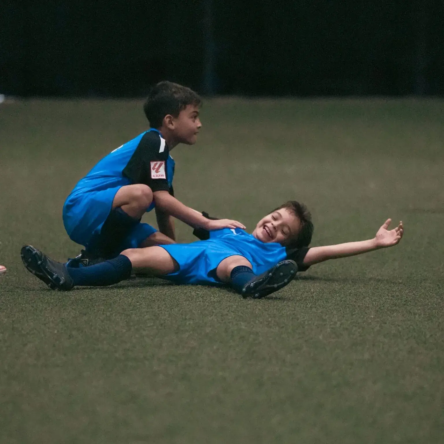 Two young boys playing football on a grass field.