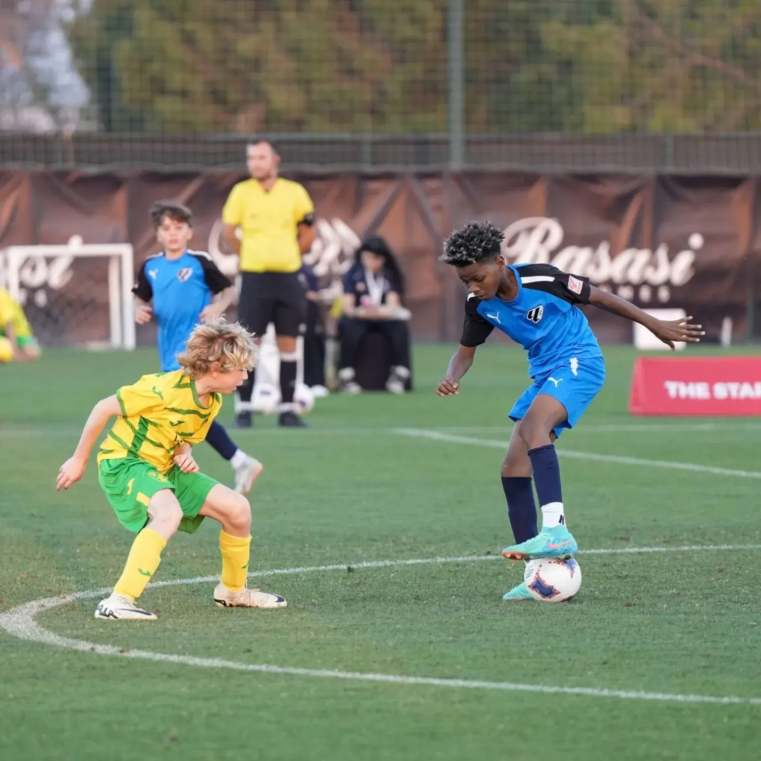 Young boys playing soccer on a field, kicking a ball and running around, enjoying a friendly match at Mina Cup 2024.