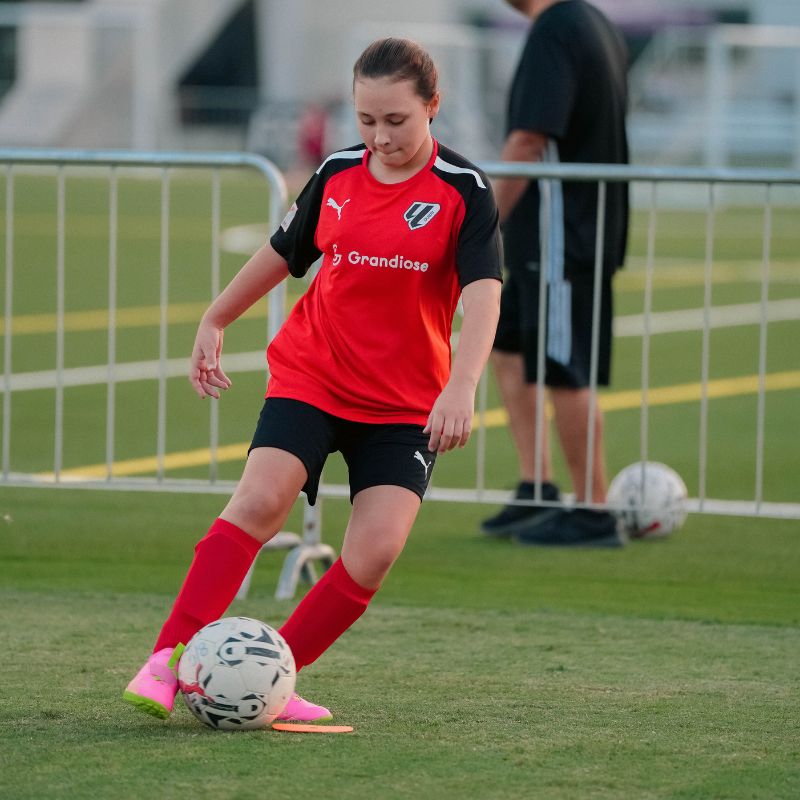 A young girl dribbling a football at laliga academy dubai in ISD Dubai Sports City