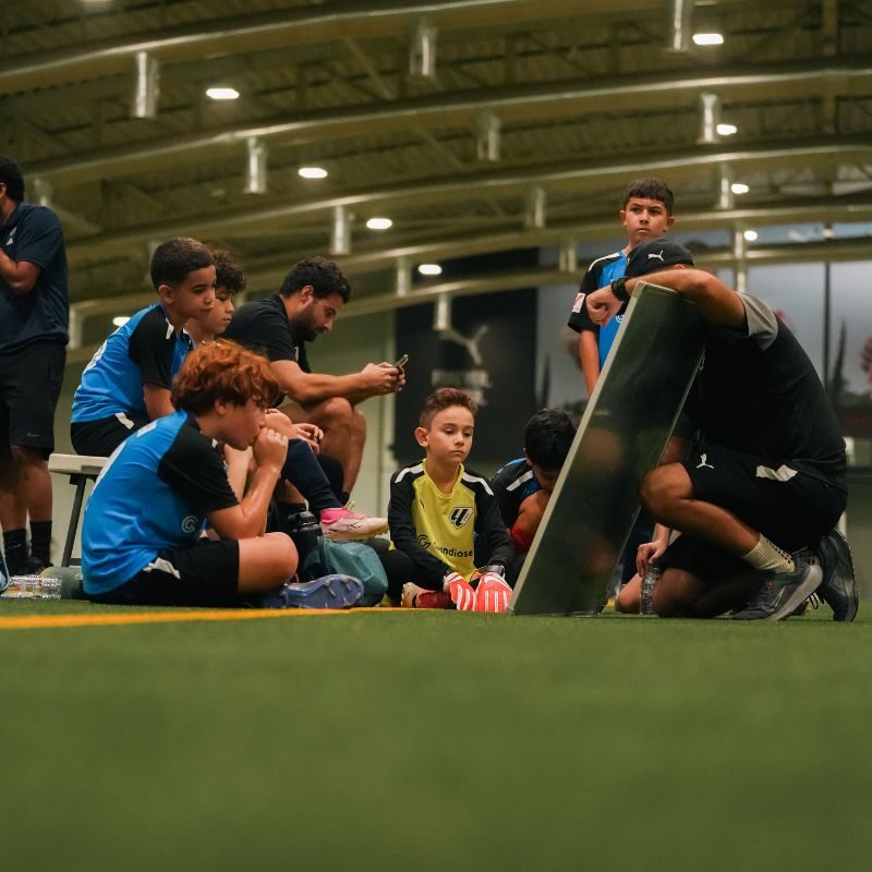 Football coaches explaining game tactics to young players below the age of 12 at laliga academy dubai in Dubai Sports City