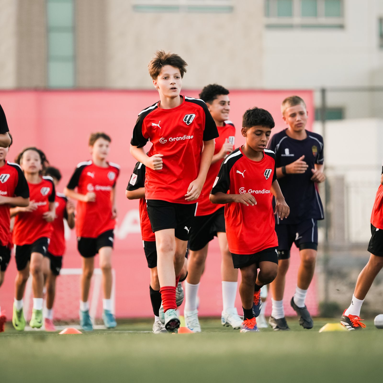 A football team of young boys warming up during their Football Coaching in Dubai Sports City at LaLiga Academy Dubai